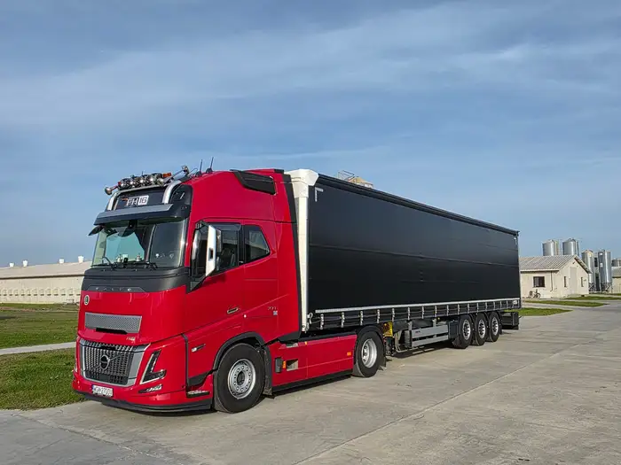 Czerwone Volvo FH16 z czarną naczepą kurtynową, ujęcie z przodu